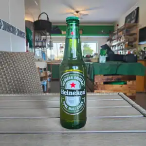 Alt: Garrafa de Heineken gelada destacada em ambiente interior de loja ou armazém.
