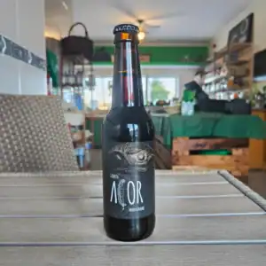 Cerveja artesanal escura com rótulo artístico em ambiente de loja de produtos frescos.
