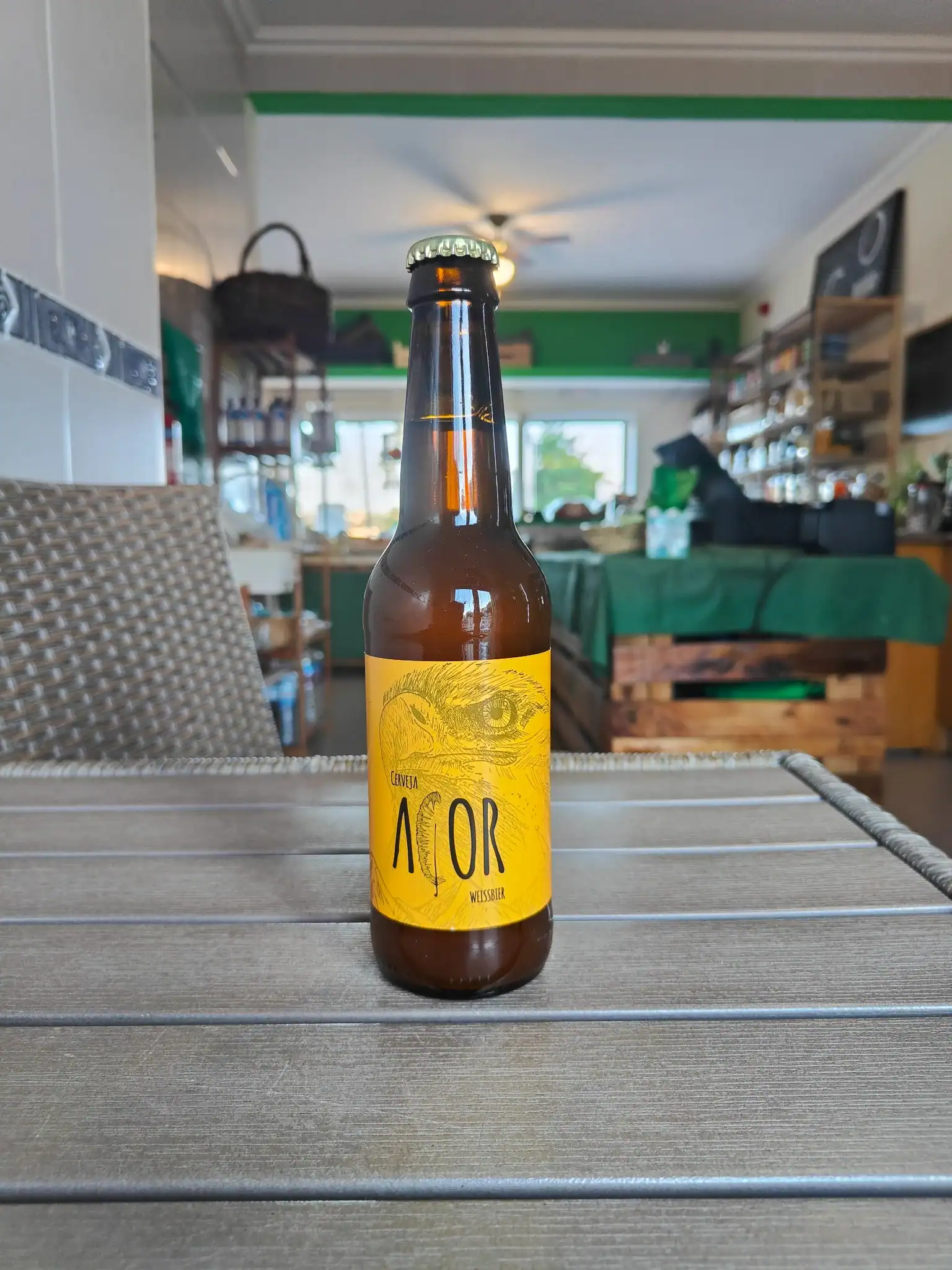 Cerveja artesanal com rótulo amarelo e ilustração de um pássaro, ideal para amantes de bebidas especiais.