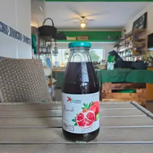 Alt text: Garrafa de sumo de romã orgânico e natural numa loja de produtos frescos.