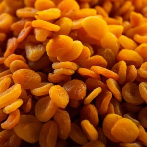 A detailed close-up image of a heap of vibrant orange dried apricots, showcasing their texture and freshness.