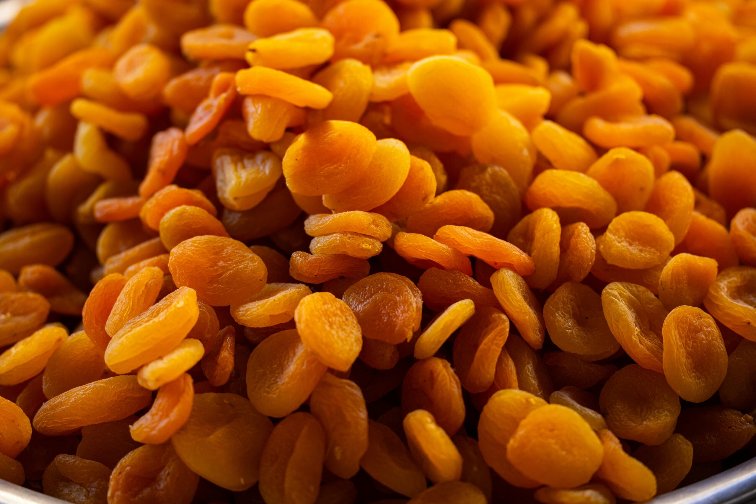 A detailed close-up image of a heap of vibrant orange dried apricots, showcasing their texture and freshness.